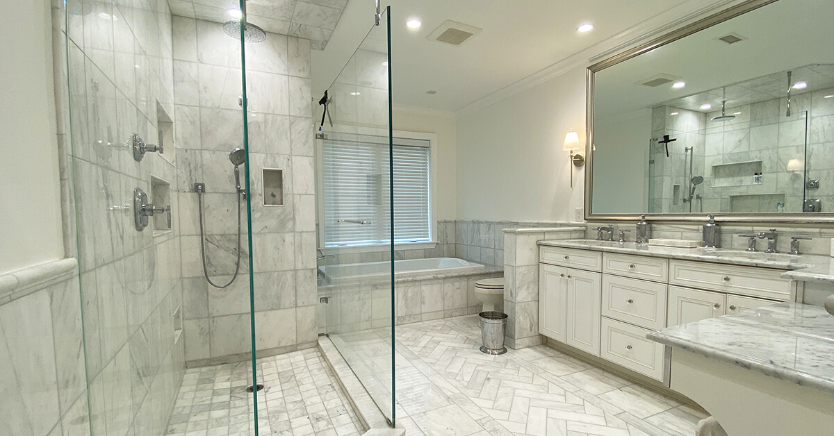Large luxury marble bathroom featuring full marble walls, shower ceiling, and floors, with a double sink vanity, marble countertops, makeup area, and oversized light gray framed mirrors in Monmouth County NJ.