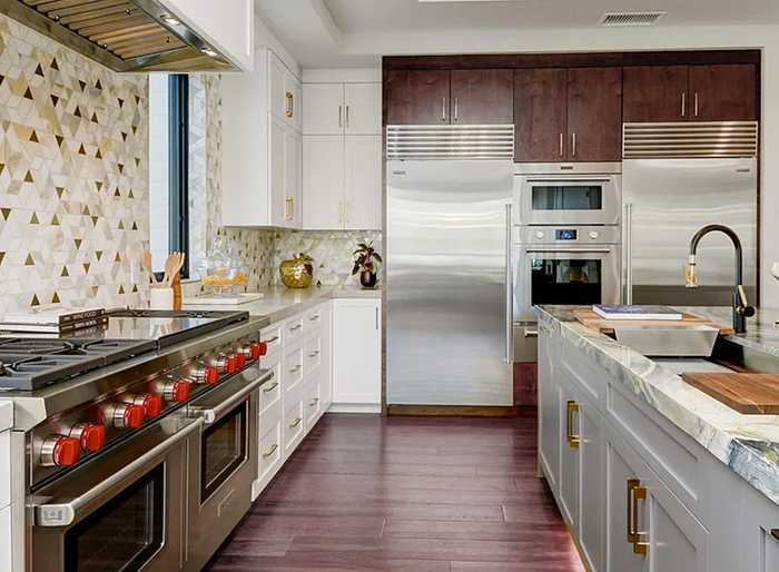 Stainless steel Subzero refrigerator and freezer separated by a stainless double oven.