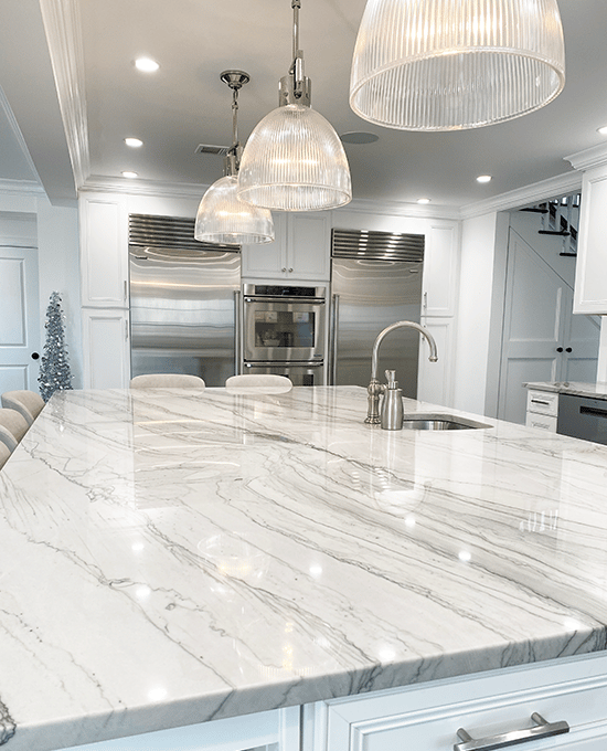 Large Quartzite kitchen island with high end bar stools, appliances, cabinetry and floors